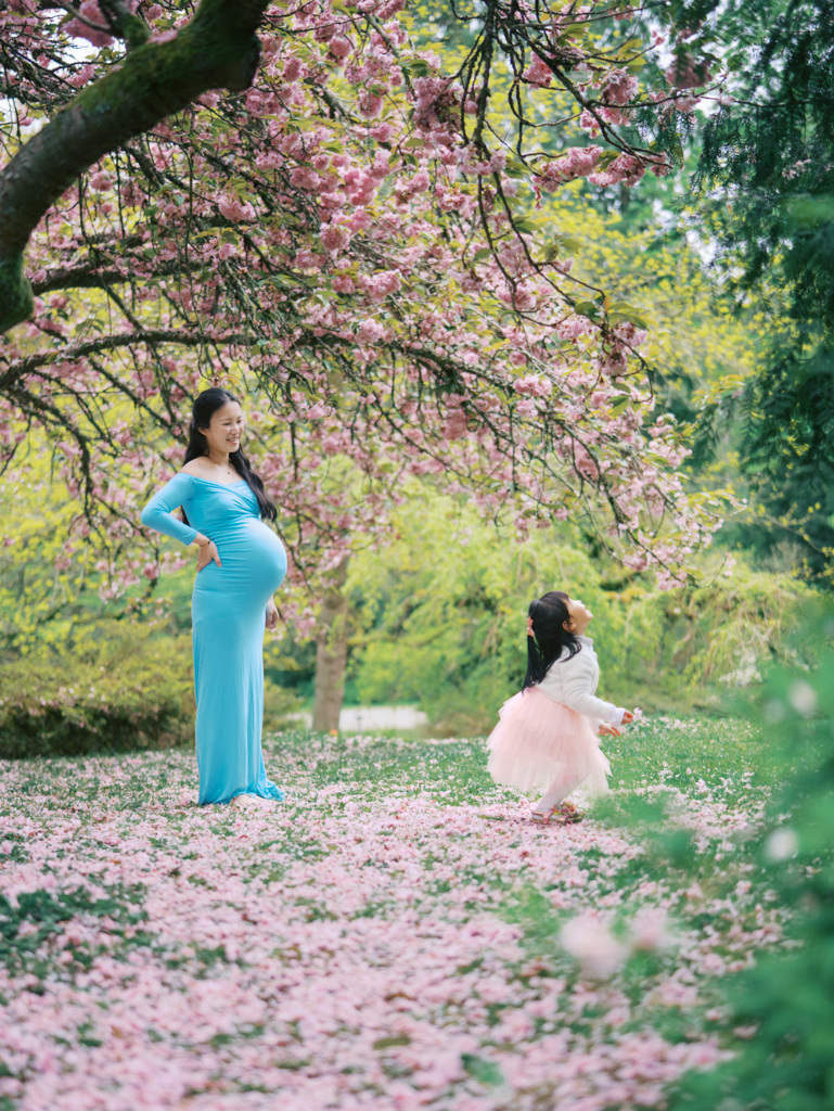 Mom watching daughter play in cherry blossoms by Seattle photographer Tanya Zagumenov