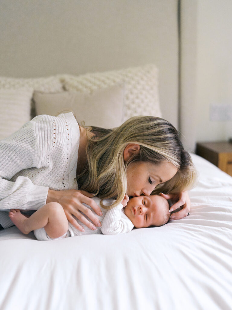 Mom kisses baby on the bed 