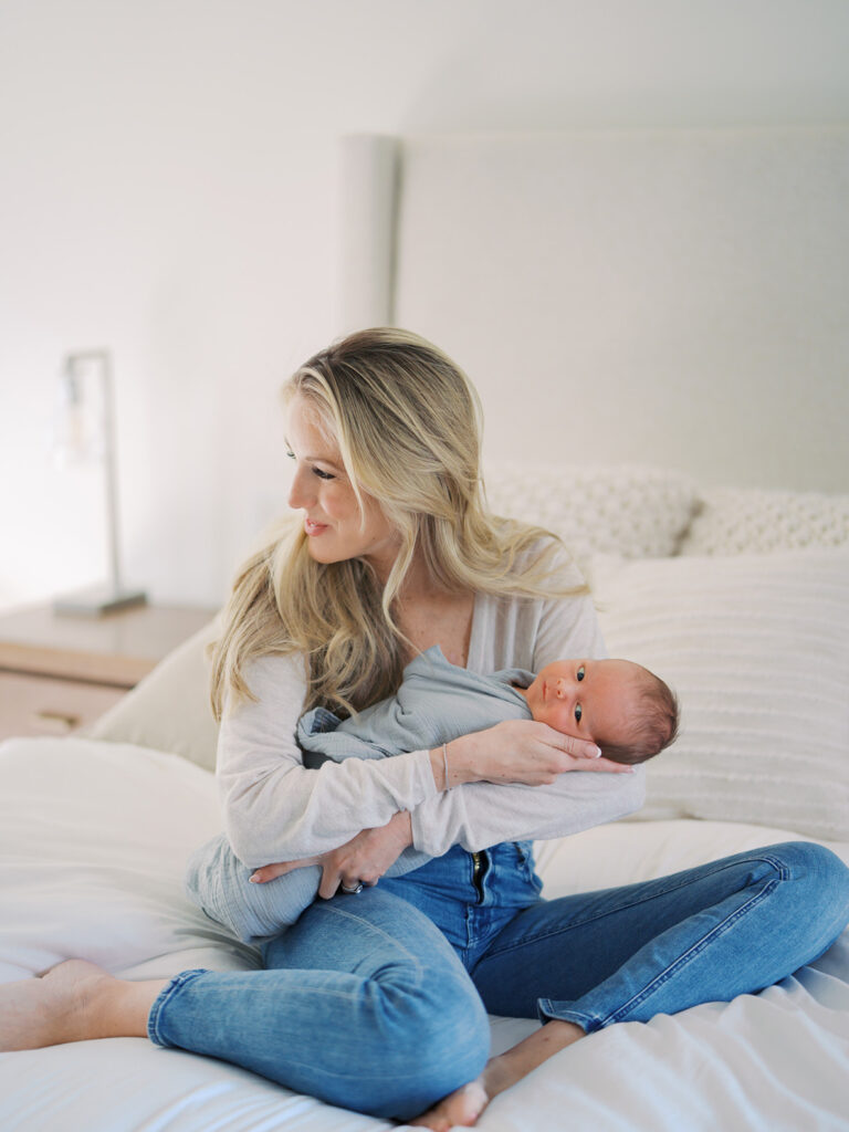 Mom cuddles baby on the bed 