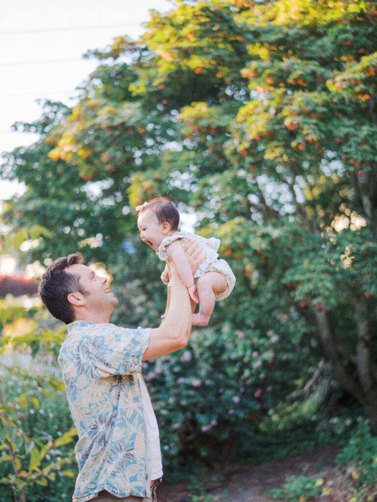 Dad tosses baby up in the air during a backyard family session in Seattle