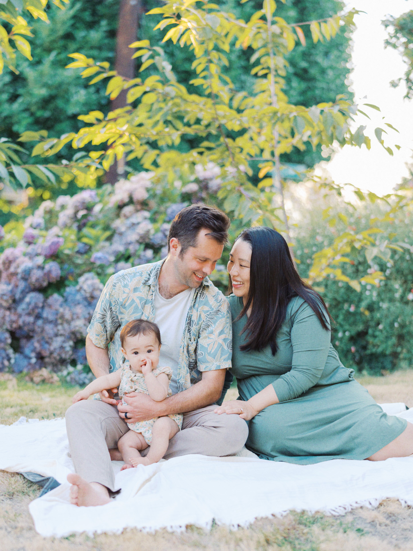 Family sitting on the blanket in their backyard and laughing during their backyard family session