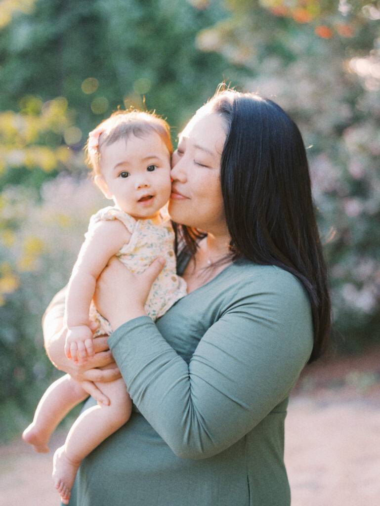 Mom kisses baby in a backyard family session in Seattle