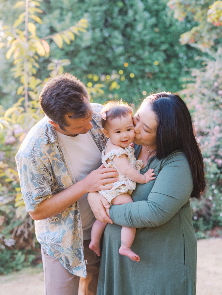 Mom and dad snuggle their baby during their backyard family session in Seattle