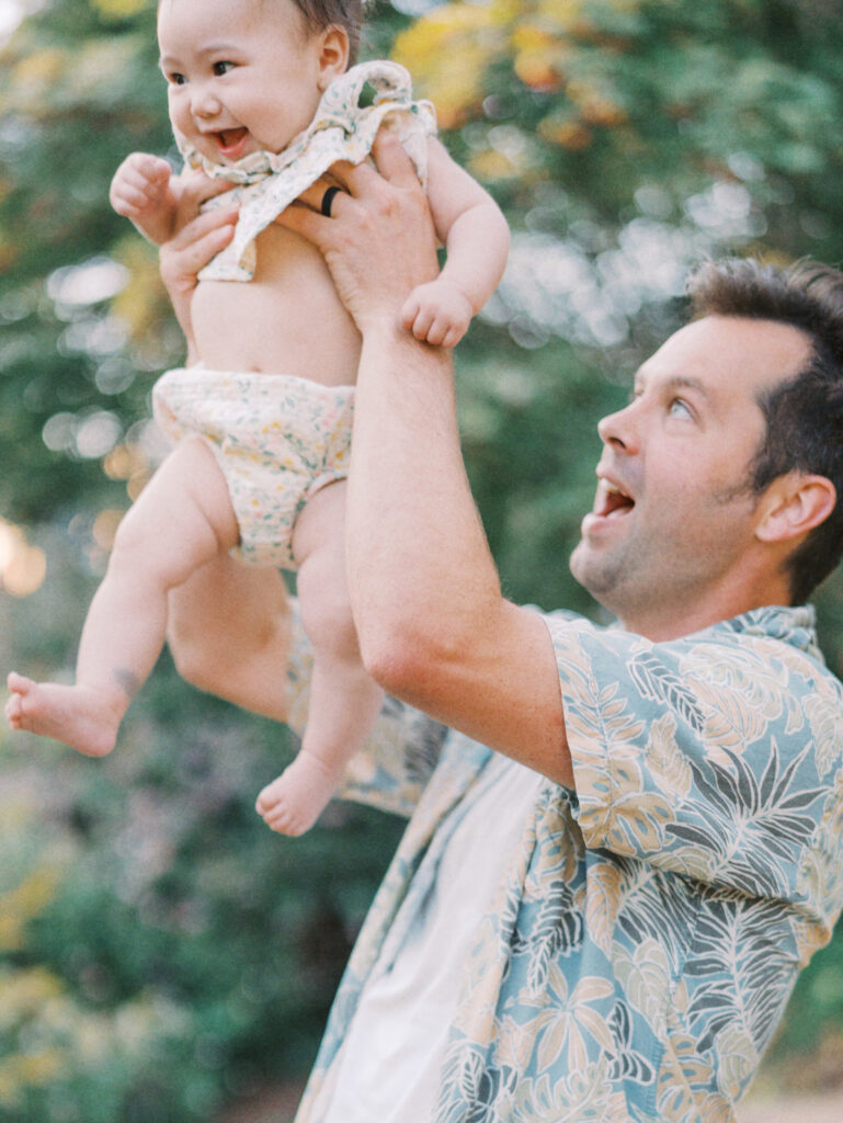 Dad gets playful with a baby in the backyard family session.
