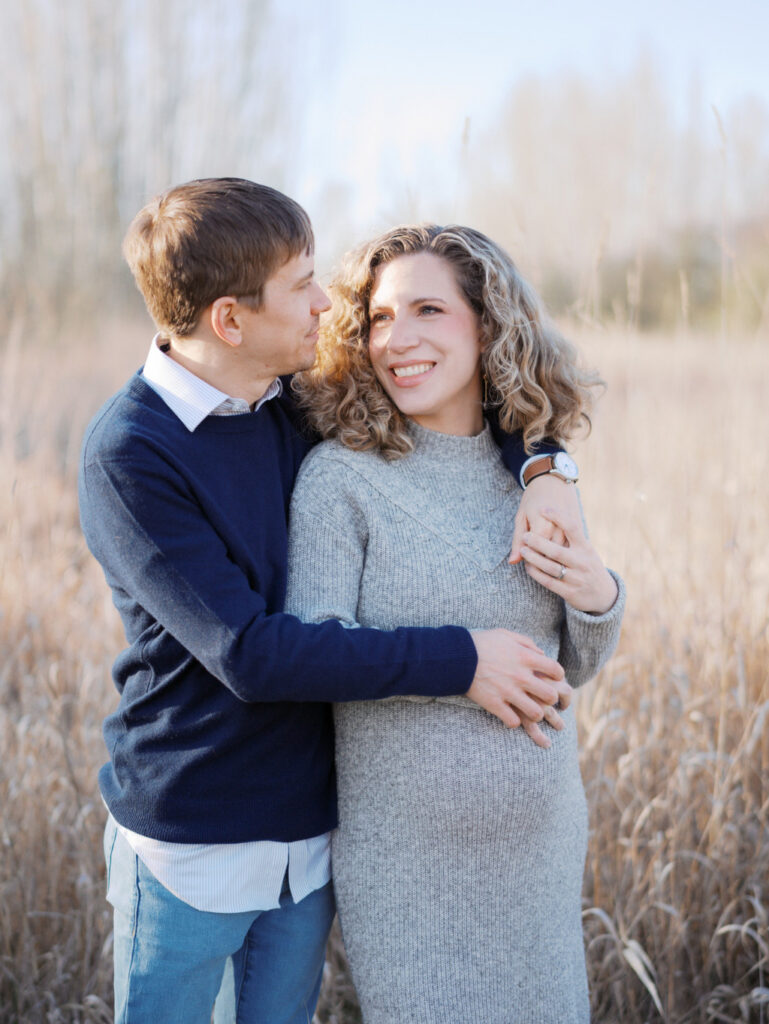 Expecting couple embracing in a grassy field in a Seattle park
