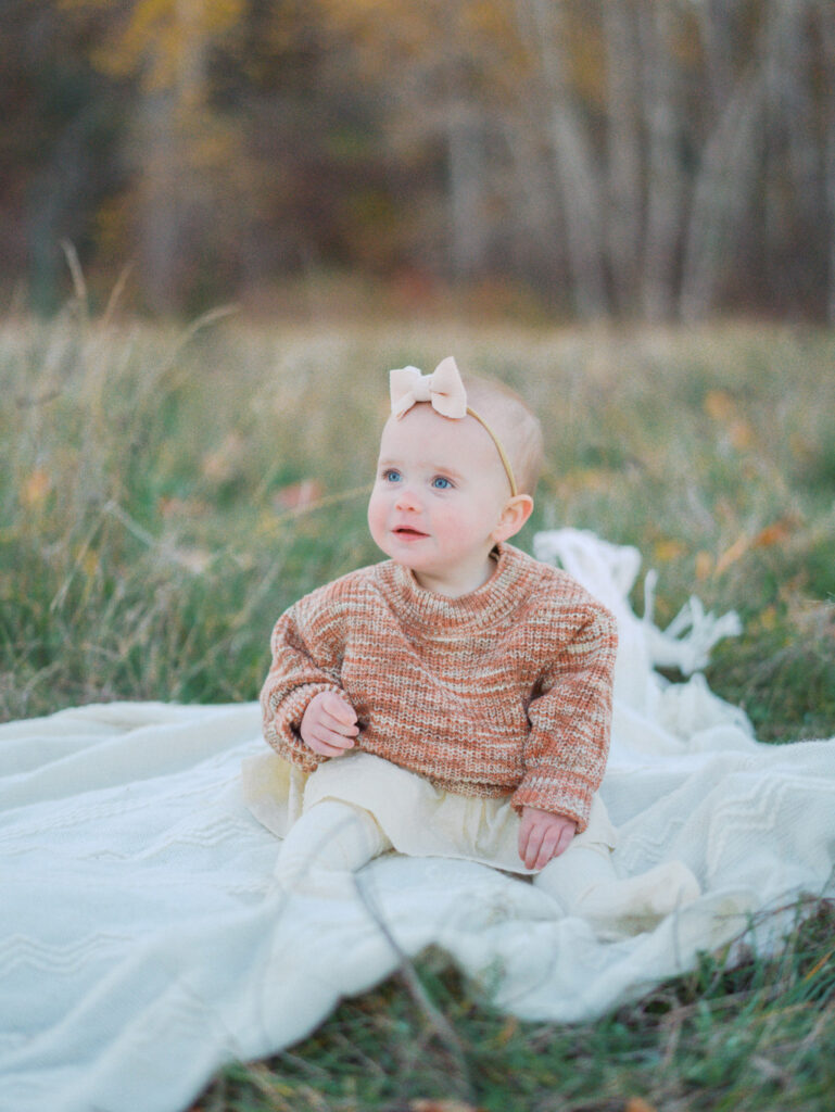 Baby sitting on a blanket looking cute after getting her parents researched baby stores in Seattle