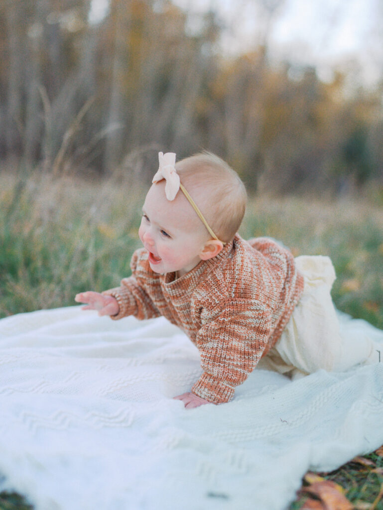 Cute baby crawling on a blanket after her parents researched baby stores in Seattle