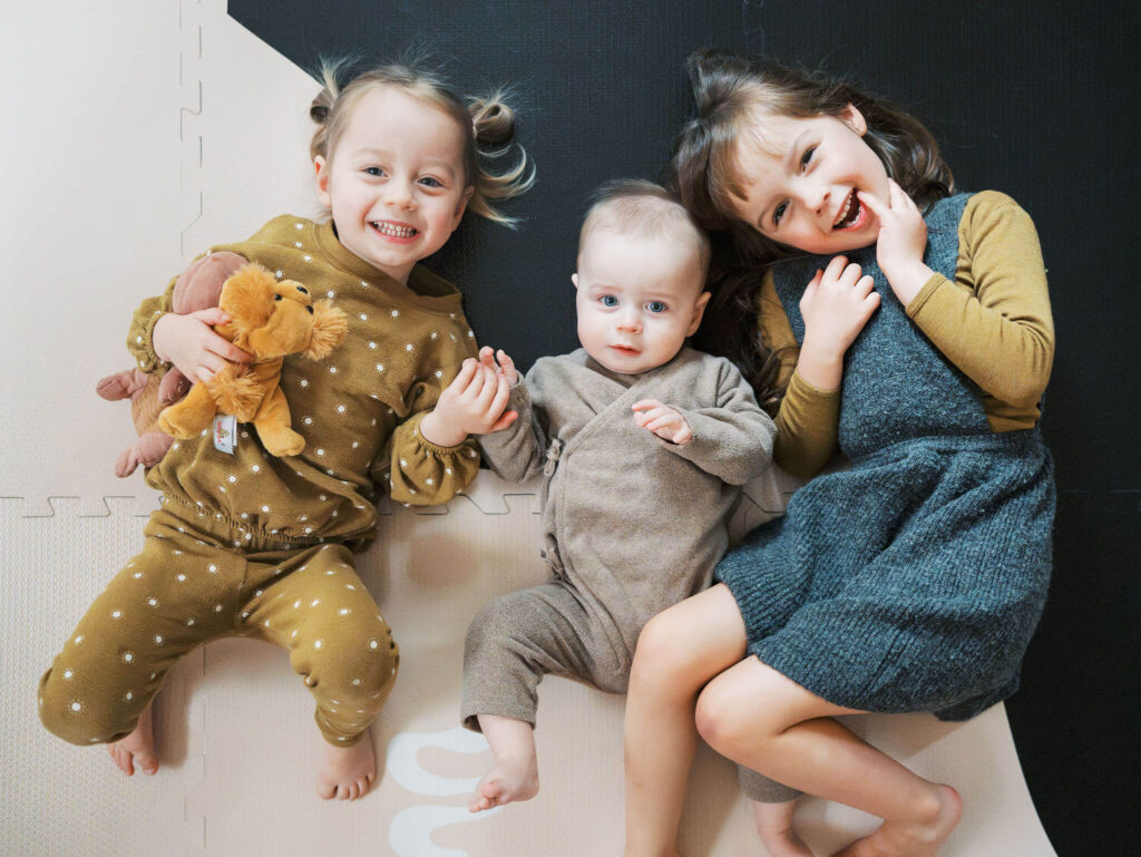 3 cute kids who shop in seattle baby stores laying on a mat