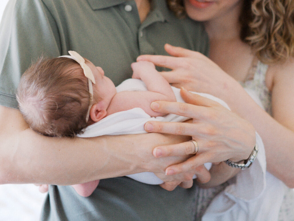 Close-up of newborn baby in parents arms, hands interlocking