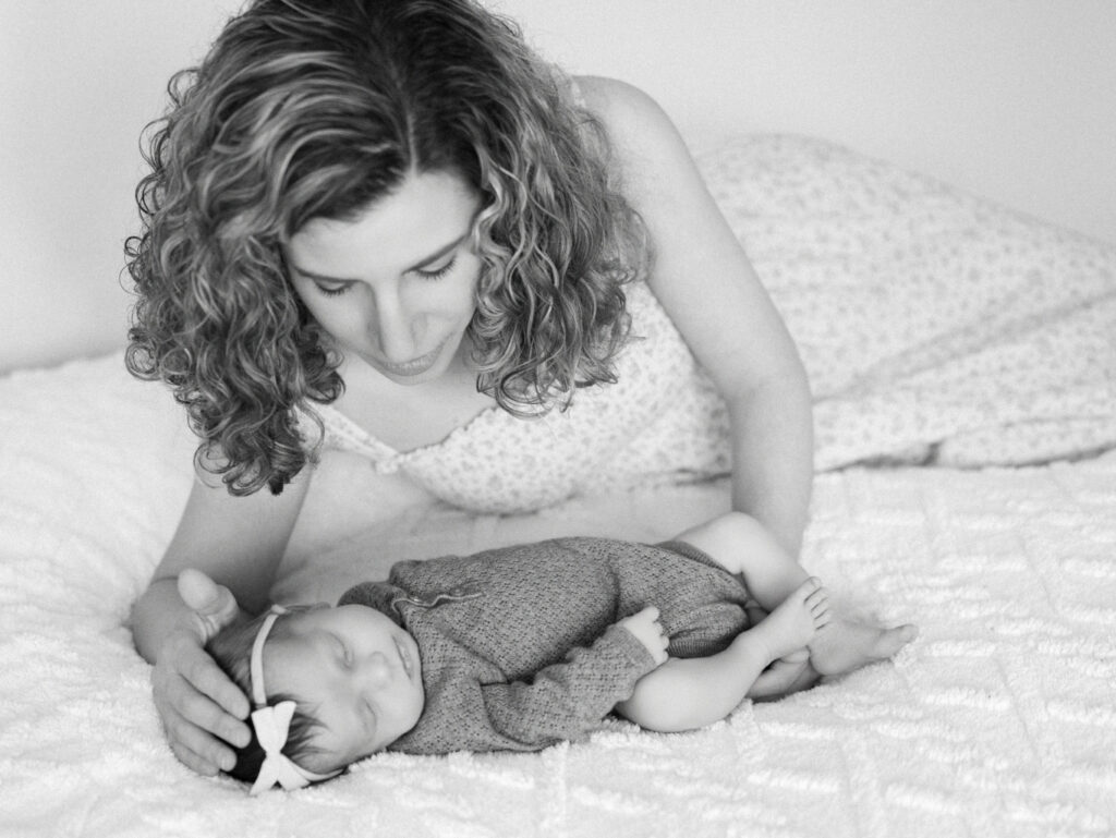 black and white image of mom snuggling a newborn baby on the bed
