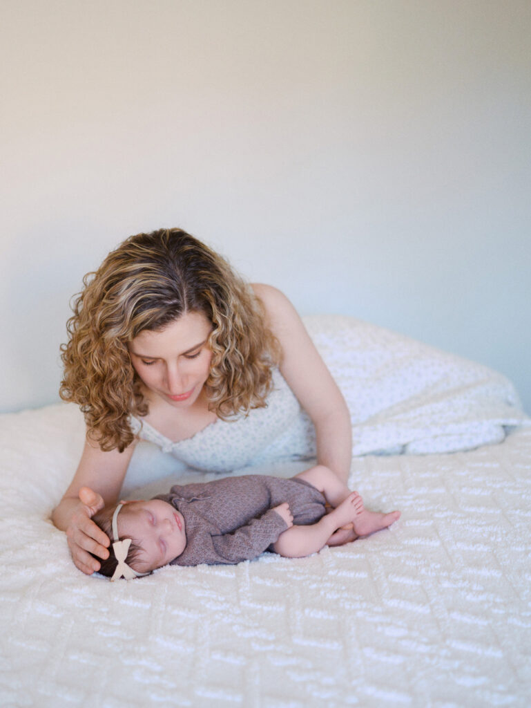 Mom laying on the bed next to her infant baby girl during a newborn session in Seattle