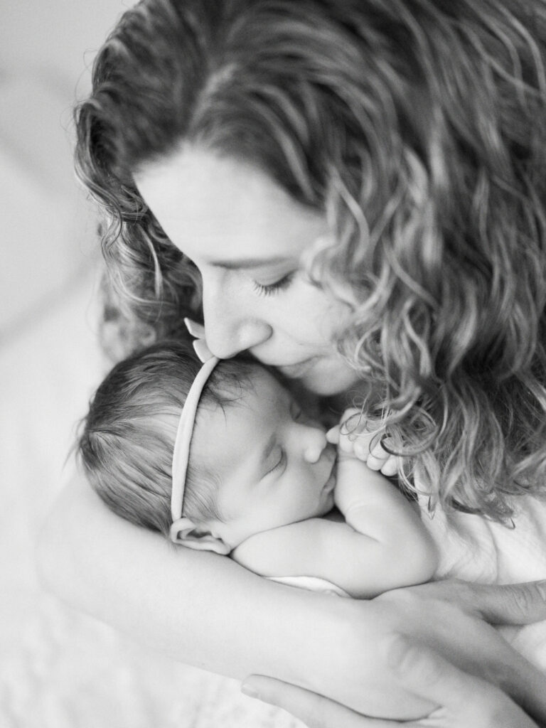 Close up of a mom kissing and snuggling her baby girl in black and white