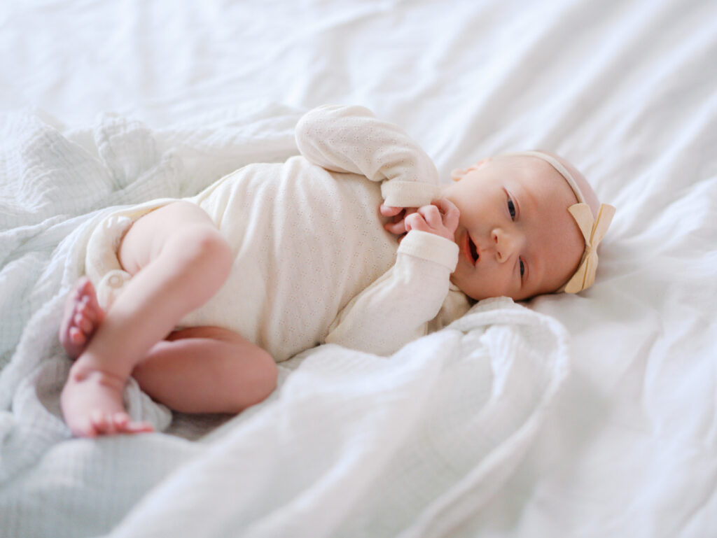 Newborn baby girl wearing a bow on the bed