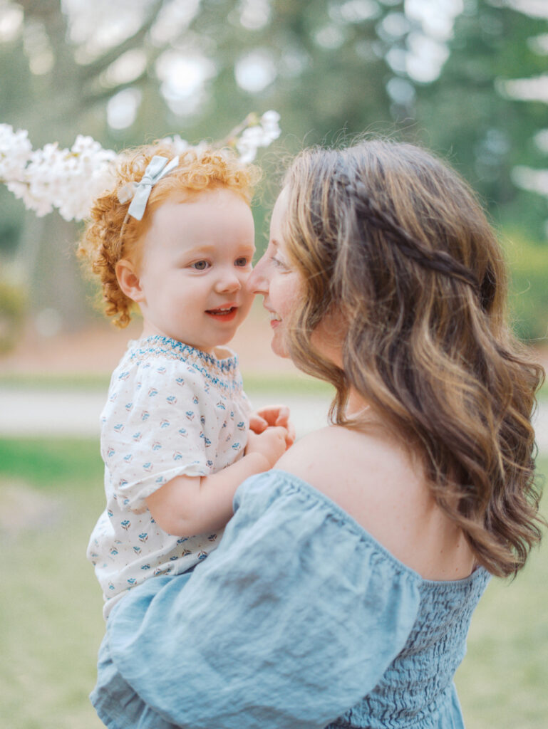 Pregnant mom and toddler daughter smiling at each other