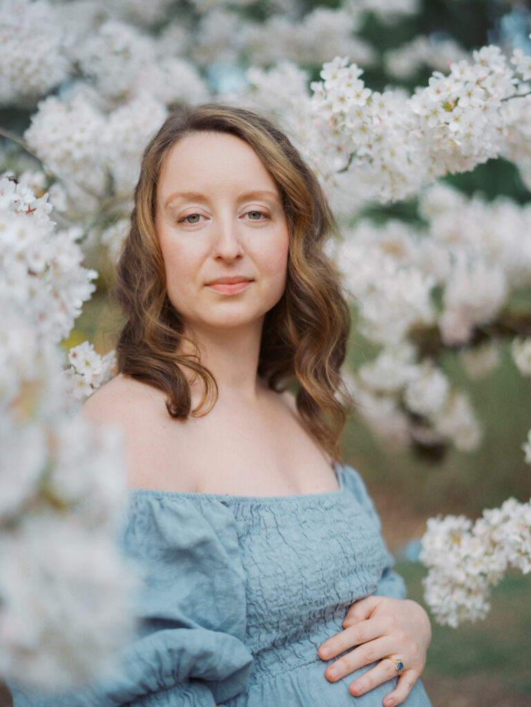Expecting mom standing surrounded by cherry blossoms after discovering top 7 Seattle obgyns.
