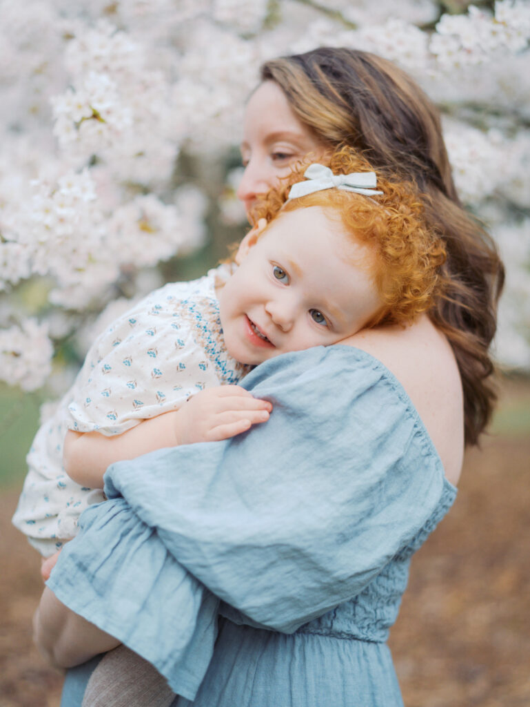 Pregnant snuggling her toddler girl with red hair