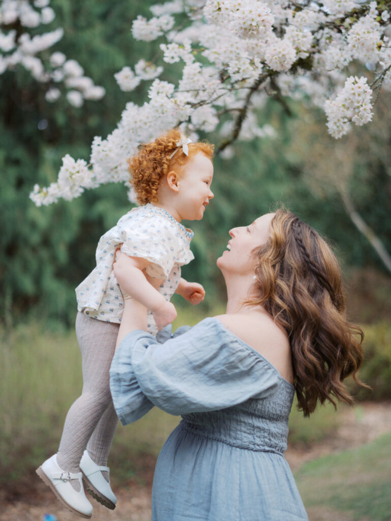 Expectant mom holding up her toddler daughter, laughing